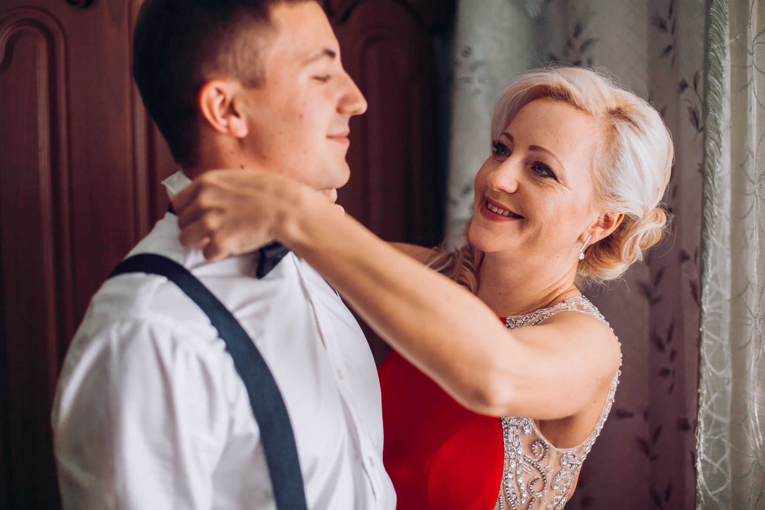 Mother Is Helping With A Bow Tie To Her Son Before Wedding Ceremony. Concept Mother And Son.