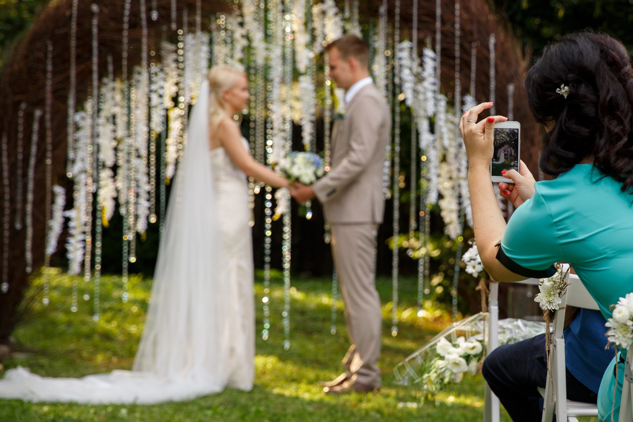 woman making promo videoblog or photo session on wedding. vlogger or journalist or blogger recording video with smartphone at wedding ceremony. selective focus on woman with smart phone